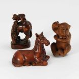 Drei Netsuke aus Buchsbaum. Alle mit schwarzen Glasaugen. Liegendes Fohlen / Affe, sich unter dem