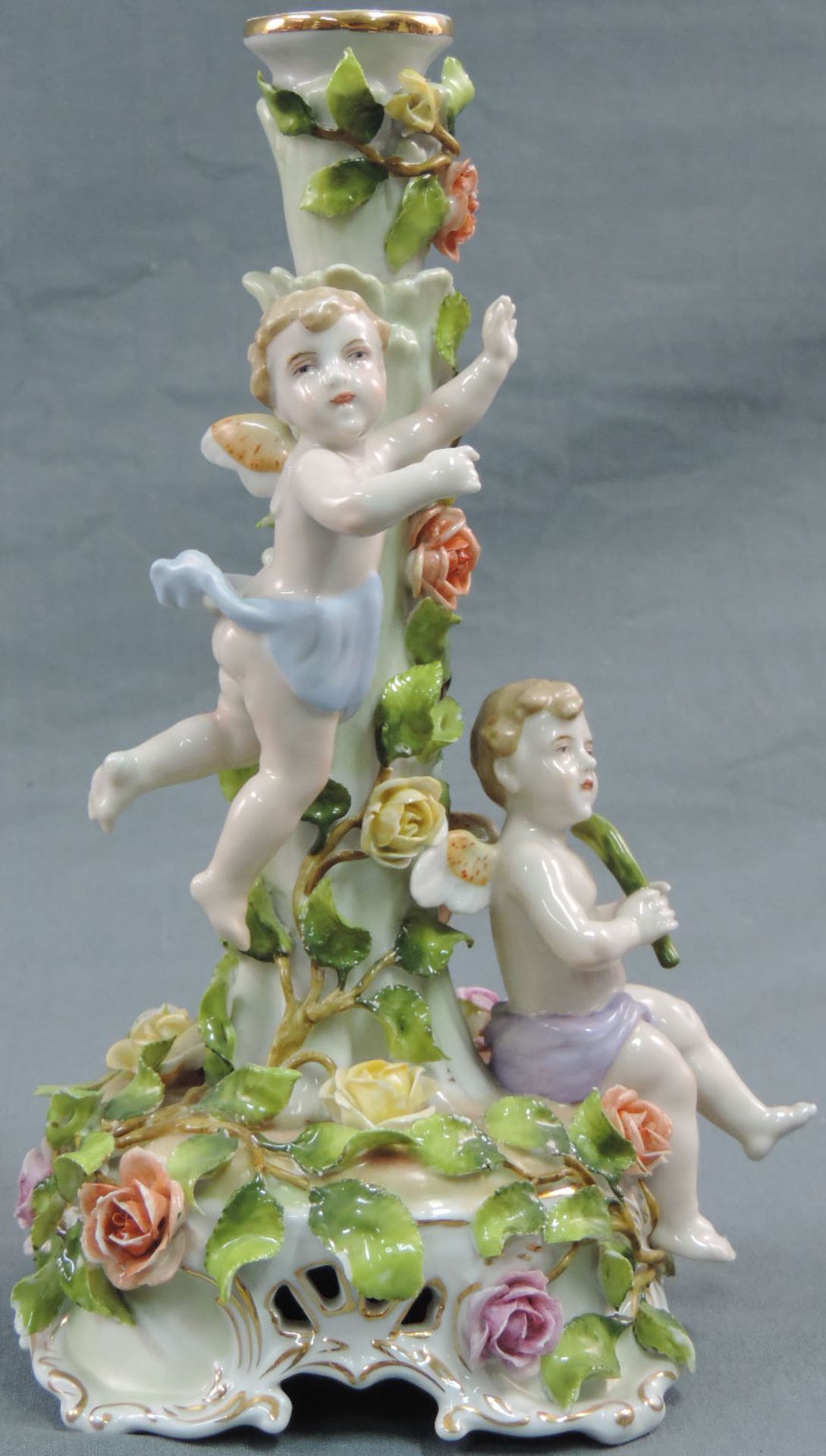 Kerzenleuchter mit Rosen und Putti.27 cm hoch. Porzellan. Beschädigungen.Candlestick with roses