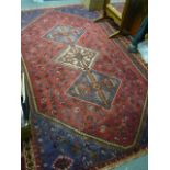 An eastern rug, the red ground with three central squares joined by a rod on a red ground with
