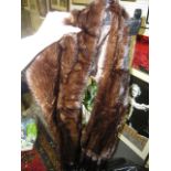 A dark brown mink fur wrap with tails (upstairs rail by silver shelves)