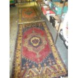 Two similar Eastern rugs, each with an elaborate central cartouche on a red ground with multiple