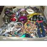 A large carton of costume jewellery, including many brightly coloured beads, bangles, etc.