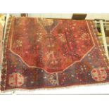 A large Eastern rug with red ground within cream geometric outer border (railings behind collector's