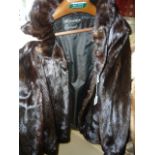 A very dark brown three-quarter length mink jacket with rolled collar, narrow cuffs and hidden front