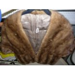 a light brown mink cape with front pocket detail and single front fastening  (upstairs rail by