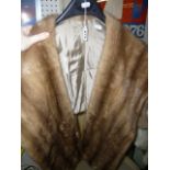 A light brown mink cape with scalloped front edge  (upstairs rail by silver shelves)