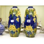 A pair of Minton Art Nouveau pottery vases, with tube-lined decoration of yellow flowers on a blue