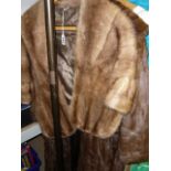 A light brown mink fur wrap with Harrods label and a full length brown squirrel fur coat (rail top