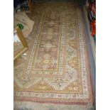 An Eastern rug, the mustard ground with a central rectangular cartouche of diamonds (floor by toy