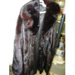 A dark brown mink fur full=length coat with wide collar, bell sleeves and hidden front fastening (