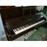 An upright piano by John Broadwood & Sons in a dark case with a stool with storage seat covered in