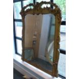 A large William IV gilt chimney glass with scrolling leaf and flower decoration.