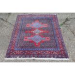 An Iranian modern hand woven rug with the red ground with two blue lozenges flanking a central cream