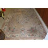 A Chinese woollen rug peach ground embossed with flowers in blues and pinks. (Hall)