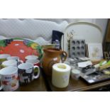 A quantity of mugs and other kitchen wares such as trays, mats, serving utensils. (Opposite S G27)