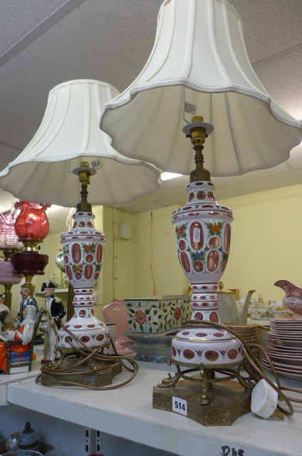 A pair of decorative white and cranberry overlay glass table lamps, enamelled with flowers, with