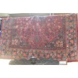 A traditional Oriental carpet, the claret red ground decorated all over with stylised flowers within