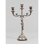 CANDELABRO IN ARGENTO, XX SECOLO con fusto decorato da cherubino e tre braccia a ramages. Misure cm.