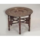 INDIAN TABLE. A carved wood Indian table with enamelled brass tray top. Diameter 77cm.