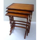 Nest of three walnut rectangular side tables, turned spindle supports, raised rims, the largest 61cm