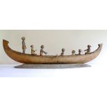 Large wooden tribal art model of a boat carrying seven carved figures, 75cm long