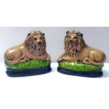 Pair of heavy painted pottery lions on black and green bases, 25cm high