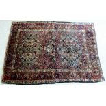 A Baluchi rug with red ground, two and a half cream medallions with dark blue foliate decoration,