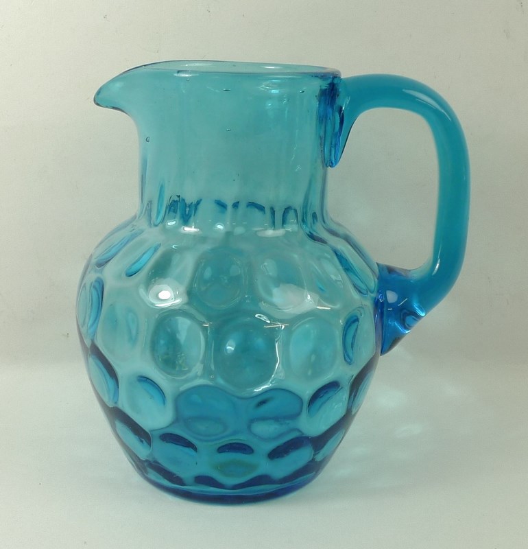 A White Friars blue glass jug, with dimple effect to bowl and ground base, 18cm high.