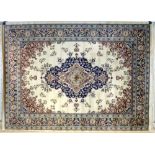 A Keshan rug with cream ground, central dark blue layered medallion and foliate field,