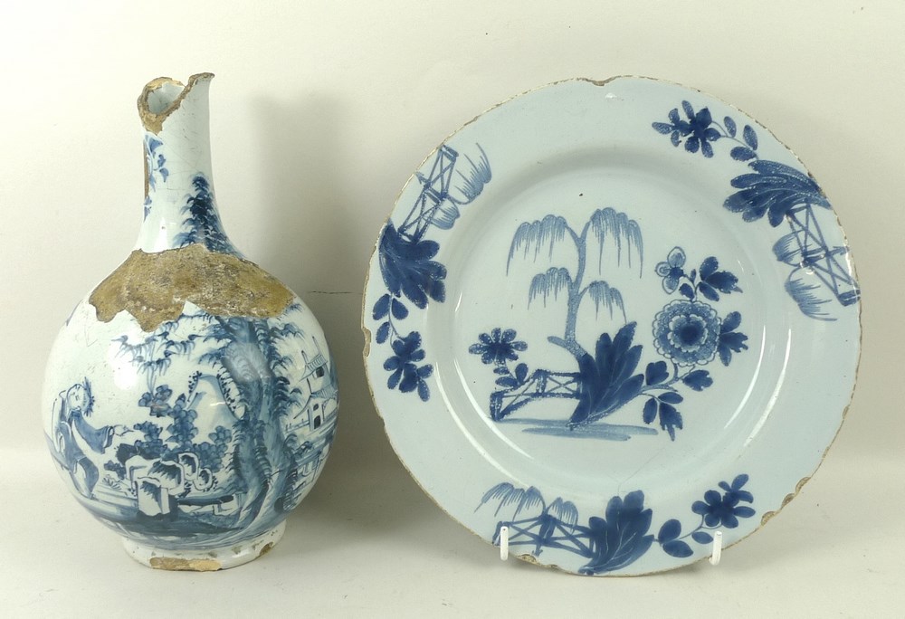 An English Delftware plate, 18th century, the blue ground decorated with a central flower and tree,