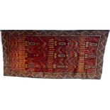 A Baluchi wide runner with red ground, decorated with three rows of totem figures,