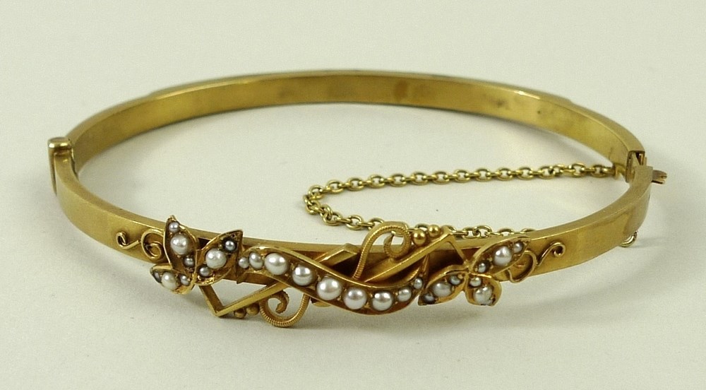 A 15ct yellow gold and natural seed pearl bangle, with trefoil and scroll motif, 12.
