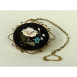 An oval pietra dura brooch, the ground set with flowers and leaves, in 9ct gold scroll form mount,