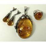 An Art Nouveau style, silver and amber pendant, the clear oval amber pendant, 3 by 4.