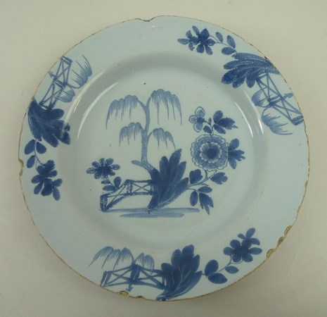 An English Delftware plate, 18th century, the blue ground decorated with a central flower and tree, - Image 2 of 11