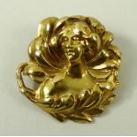 An Art Nouveau yellow metal brooch of circular design with naturalistic swirling adornments to a