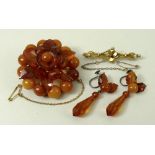 An amber floral brooch, formed as three circles of stones divided by one ring of leaves,