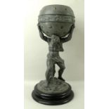 A pewter atlas, raised on a turned ebonised round base, the hero holding a celestial globe,