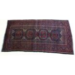 A Baluchi rug with dark red ground, four square medallions with canted corners,