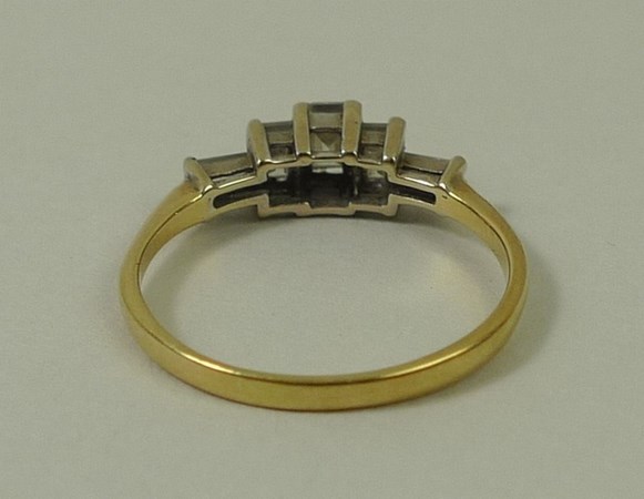 A gold and diamond ring, the central baguette cut diamond flanked by two smaller diamonds, - Image 3 of 3