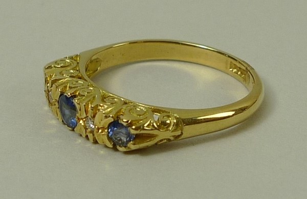 An 18ct gold, sapphire and diamond ring, set with three sapphires divided by two diamonds accents, - Image 2 of 3