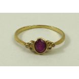 A 9ct gold ring set with a central ruby/pink amethyst, flanked either side by three diamonds,