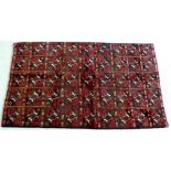 A Baluchi / Turkoman rug with dark red ground, decorated with forty five square panels in cream,