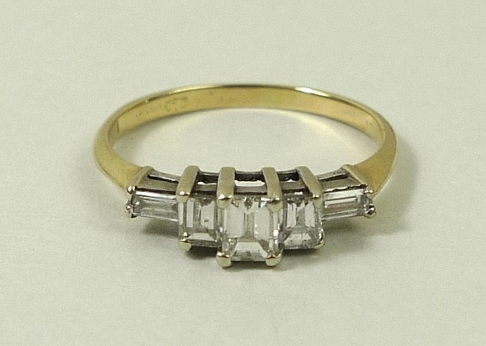 A gold and diamond ring, the central baguette cut diamond flanked by two smaller diamonds,