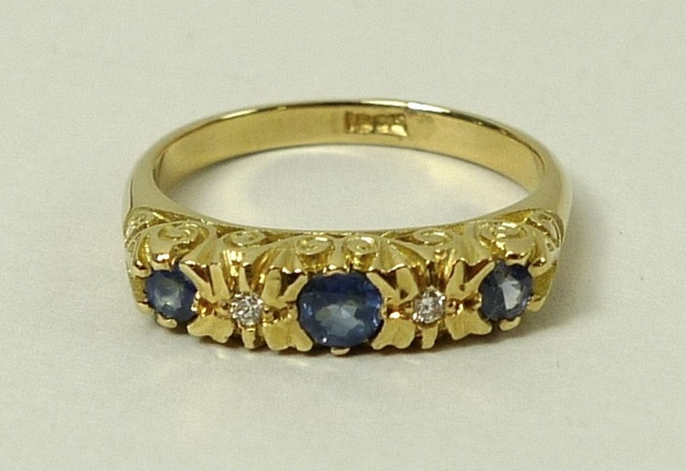 An 18ct gold, sapphire and diamond ring, set with three sapphires divided by two diamonds accents,