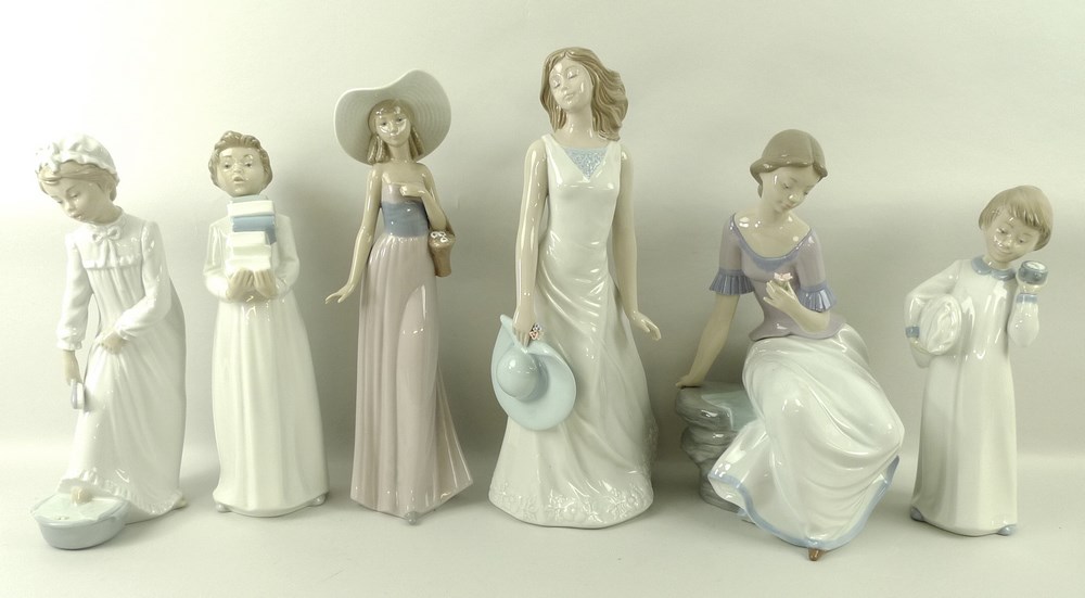 A group of Nao figurines, comprising a boy in nightshirt, a girl in nightgown, a boy carrying books,