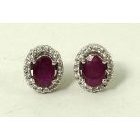 A pair of ruby and diamond stud earrings, the central ruby approximately 2.
