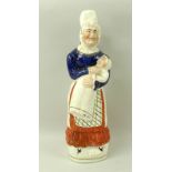 A Staffordshire figurine of Judy (Mrs Punch) holding a baby, 19th century, hand painted in blue,