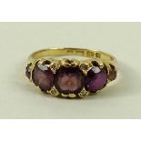 An 18ct gold and amethyst ring, the central amethyst flanked by two smaller amethysts, size Q.