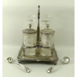 A George III silver cruet set, the silver base with hoop handle, gadrooned edge,